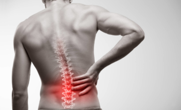 Athletic man with lower back pain highlighted by a red light.