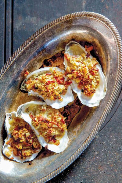 A tray of oysters Rockefeller with bacon--baked oysters topped with bread crumbs, bacon, and butter.