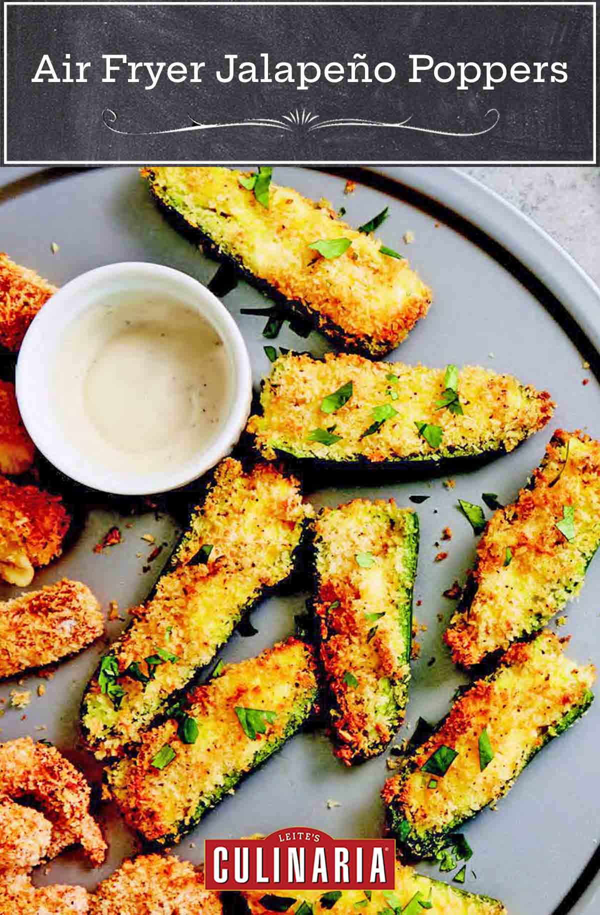 A grey plate filled with jalapeño popper halves and a bowl of white dip on the side.