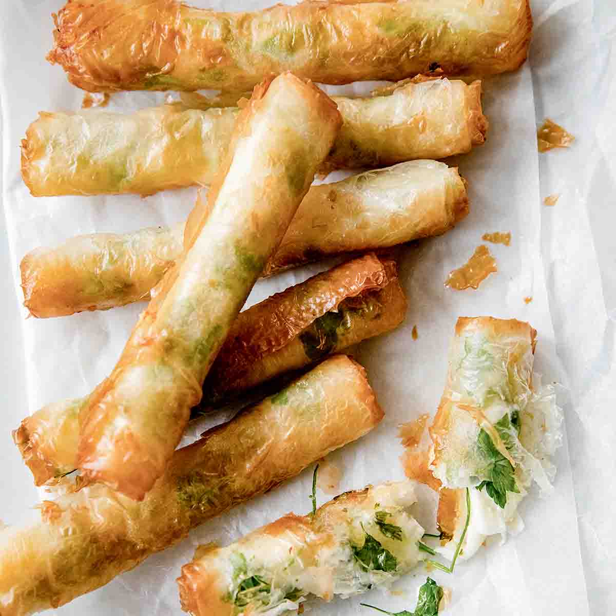 Seven crispy rakakat (Turkish cigars) on a parchment-lined white plate.