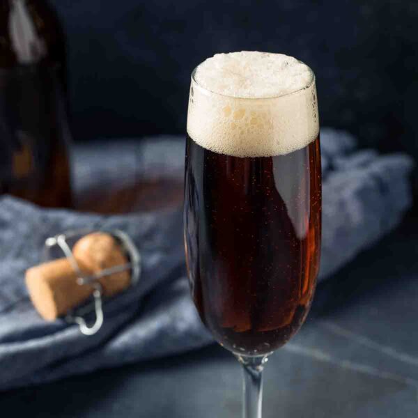 A black velvet cocktail in a flute with a napkin and cork in the background.