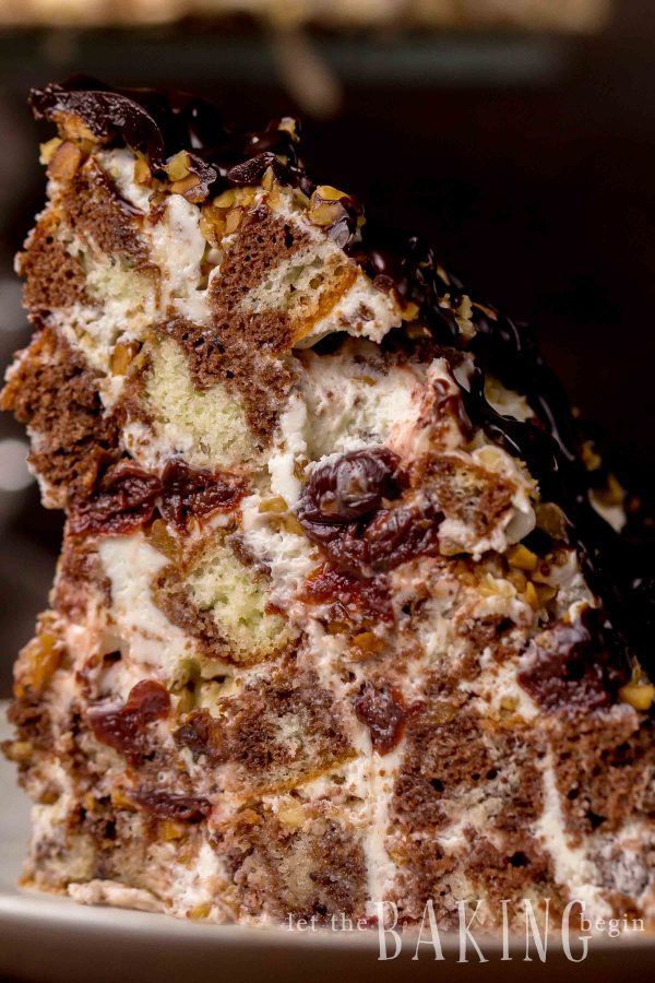 Slice of marble cake topped with chocolate on a white plate.