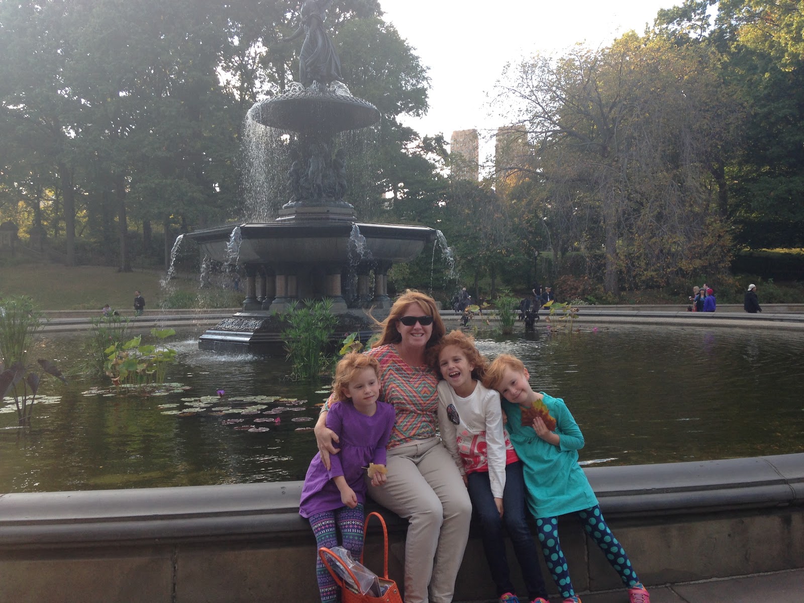 mom and kids in central park taking a family photo near New York City fountain
