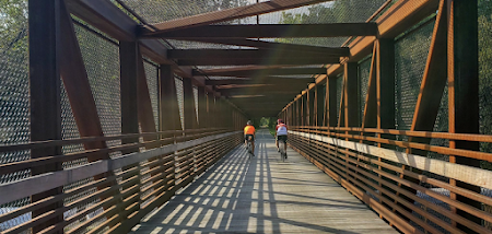 Two people riding bicycles on a bridge