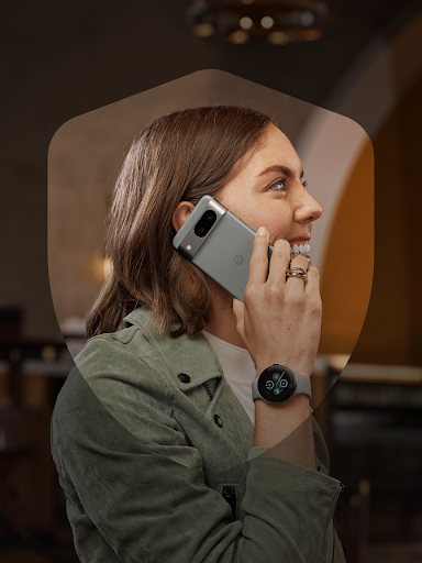 A smiling Android user securely takes a phone call while showing off their Pixel Watch 2. The user is framed by a shield icon.