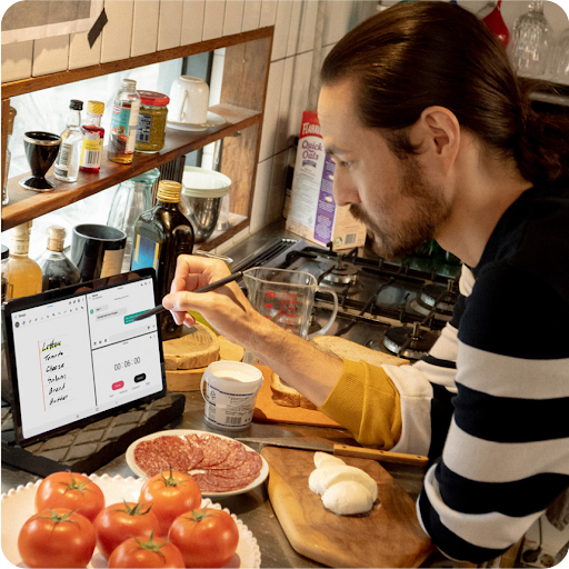 A person with a stylus against a tablet screen, multitasking between designing, tracking the time on a stopwatch, while chatting with a friend.