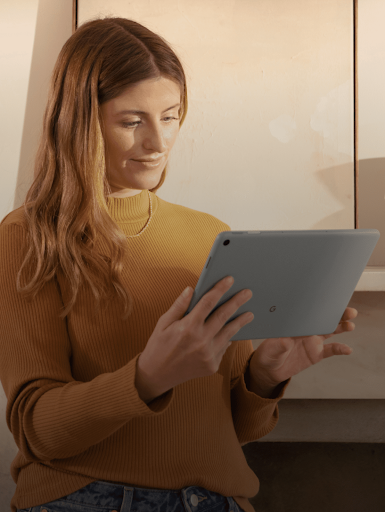 A lady smiling while looking at her tablet’s screen.