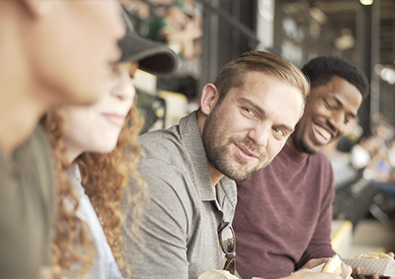 group of friends with the camera focused on one man smiling