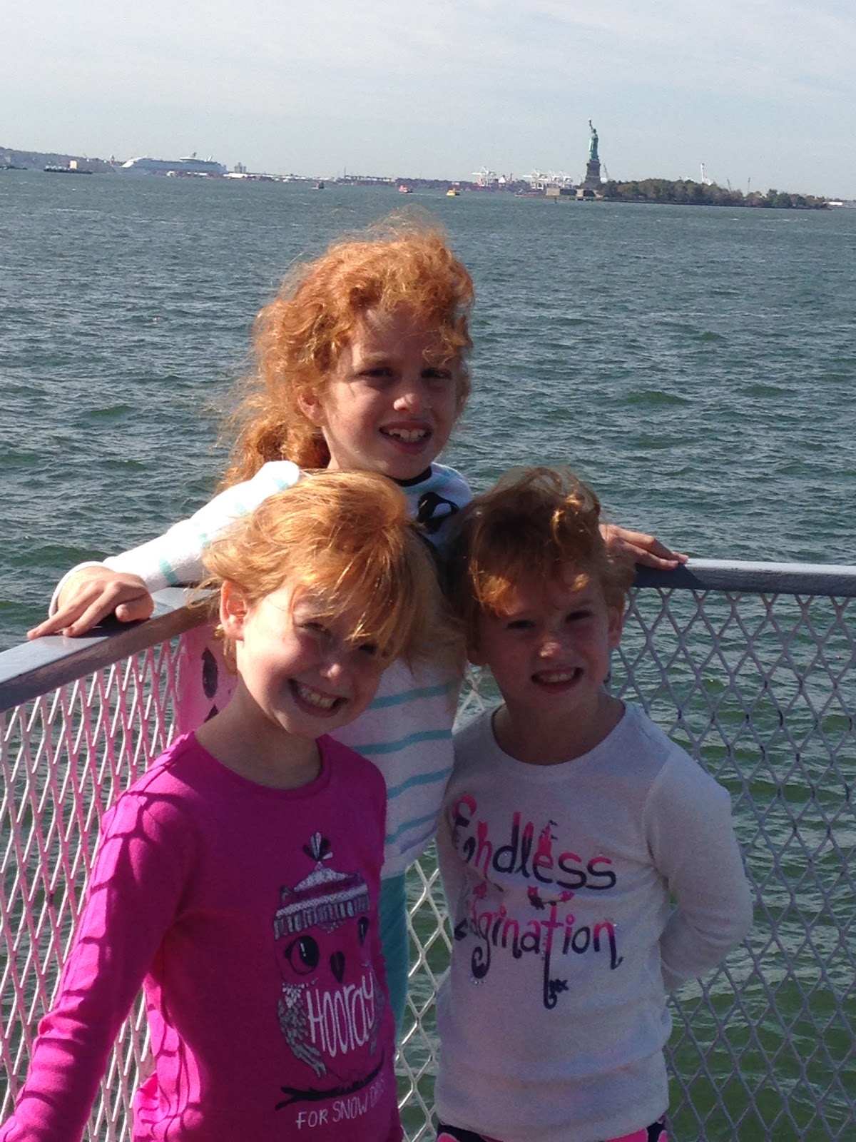 New York with Kids taking a photo with the statue of liberty in the background
