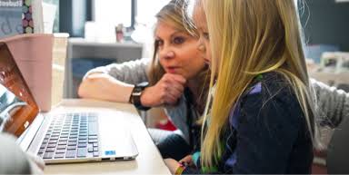 Una profesora y una alumna están frente a un Chromebook, posiblemente averiguando cómo protege Google la información de profesores y alumnos.