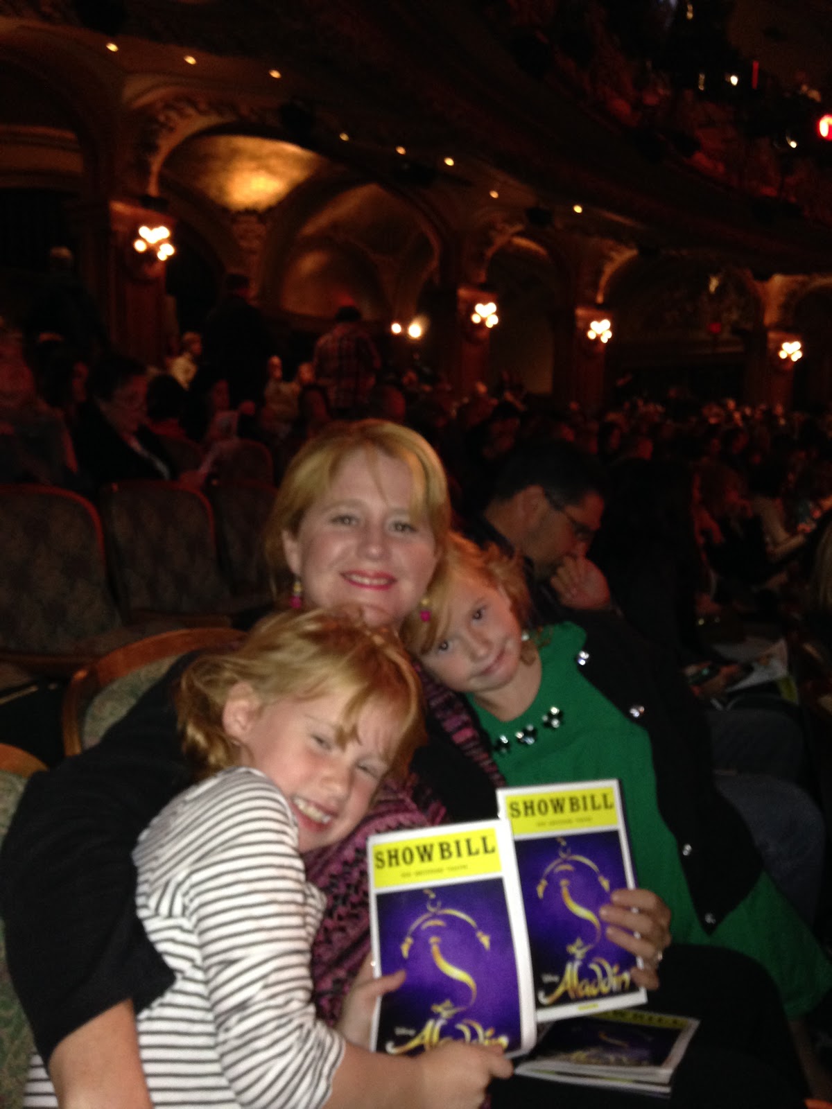 Mom and kids holding up the showbill while visiting time square and seeing a broadway show in new york.