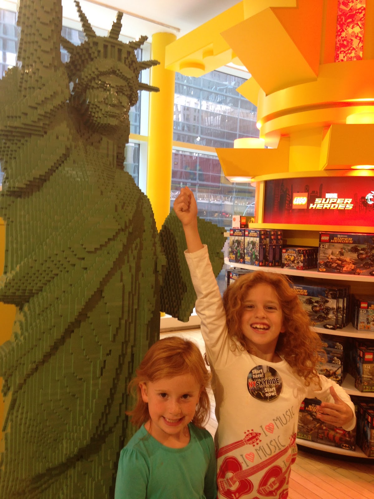 two kids standing by the Lego statue of liberty while visiting New York City with children