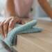 Person dusting a coffee table with a soft dust cloth