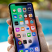 Close-up image of a person holding an iPhone against a blurred outdoor background