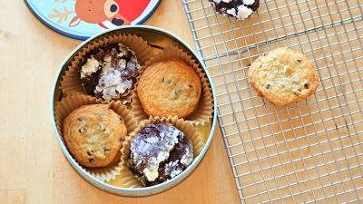 Cookies in a cookie tin next to a wire cooling rack.