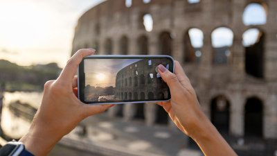 A person takes a photo of the Coliseum with their phone