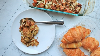 A scoop of stuffing on a plate next to a pack of croissants on a countertop.