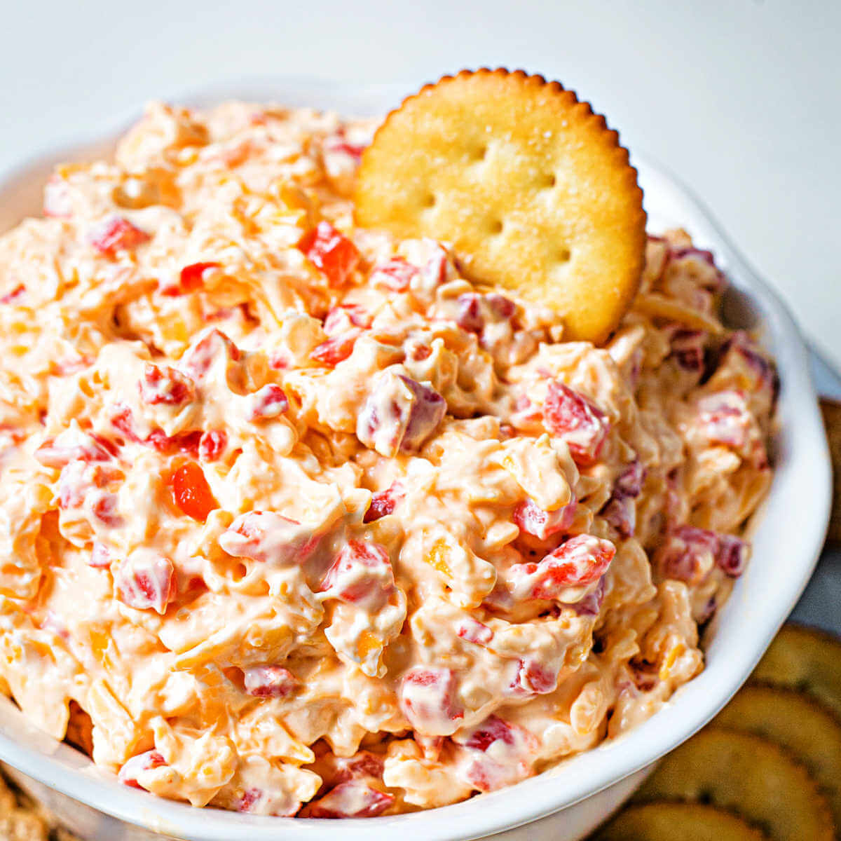 a bowl mounded full with homemade pimento cheese with crackers on a plate.