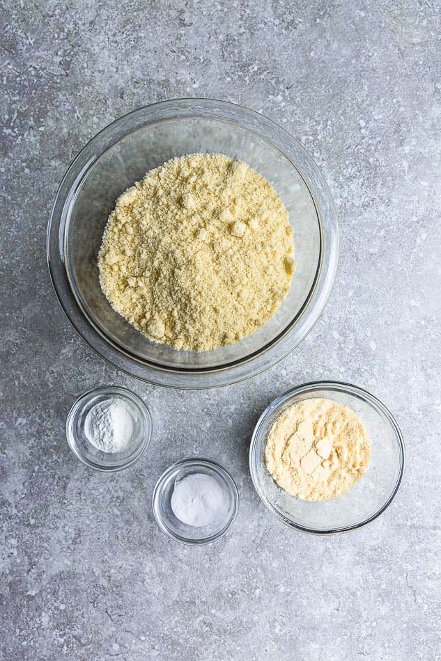 Top view of carrot cake ingredients in clear white bowls on a grey background