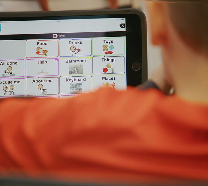 A close up of a non-verbal child using a tablet as a communication device