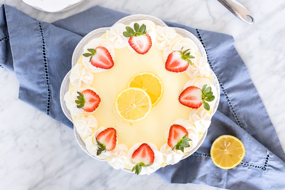 Lemon jello no bake cheesecake topped with fresh strawberries and lemon.