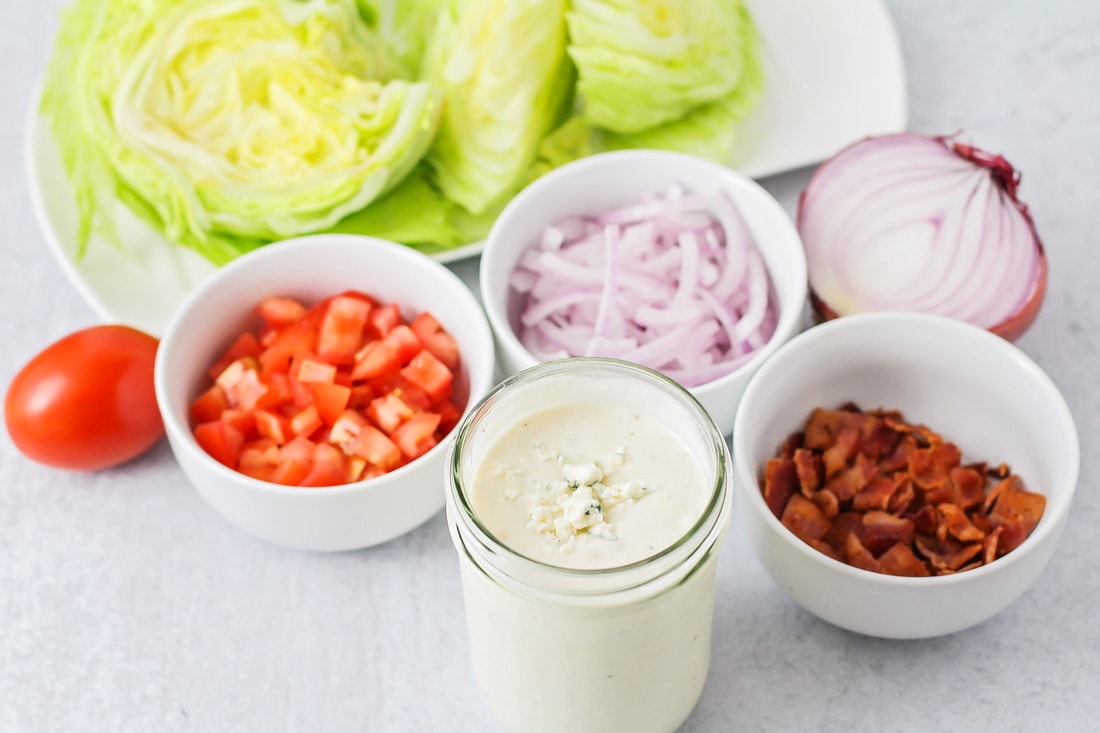 Salad ingredients separated in white cups and plates.