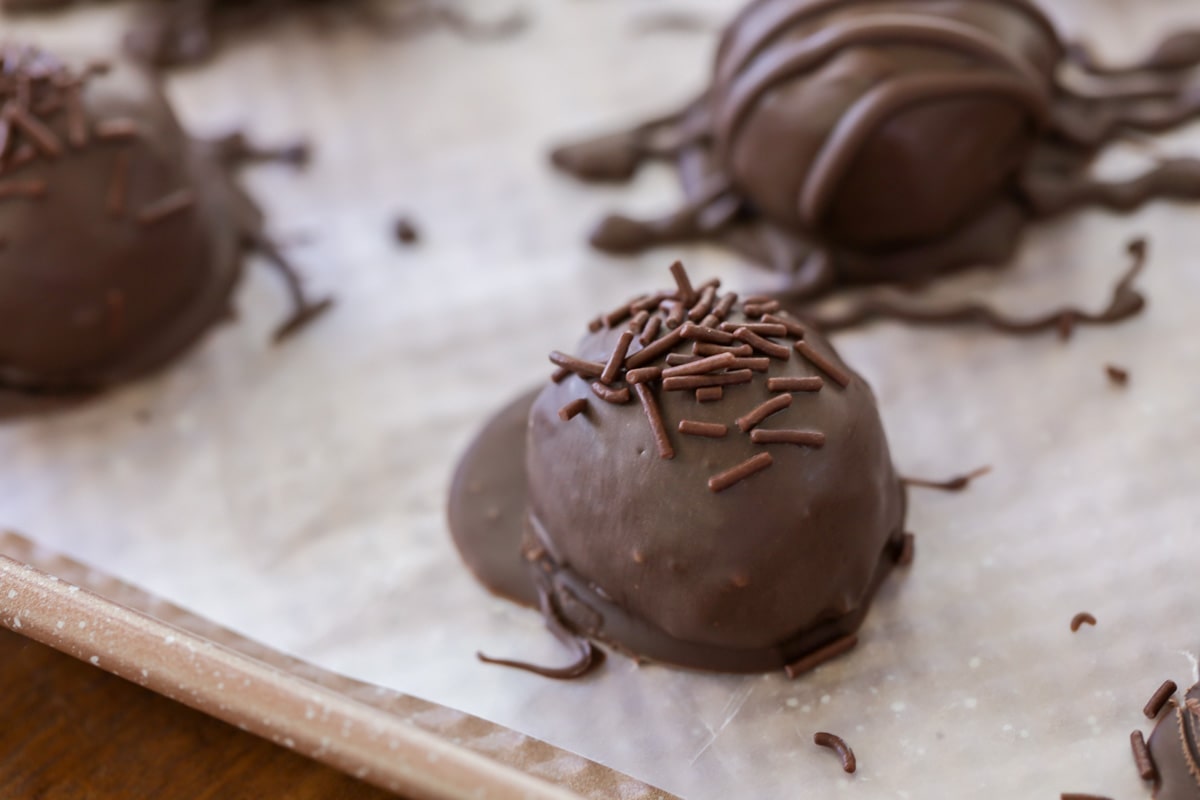 Peanut butter balls dipped in milk chocolate on parchment paper.