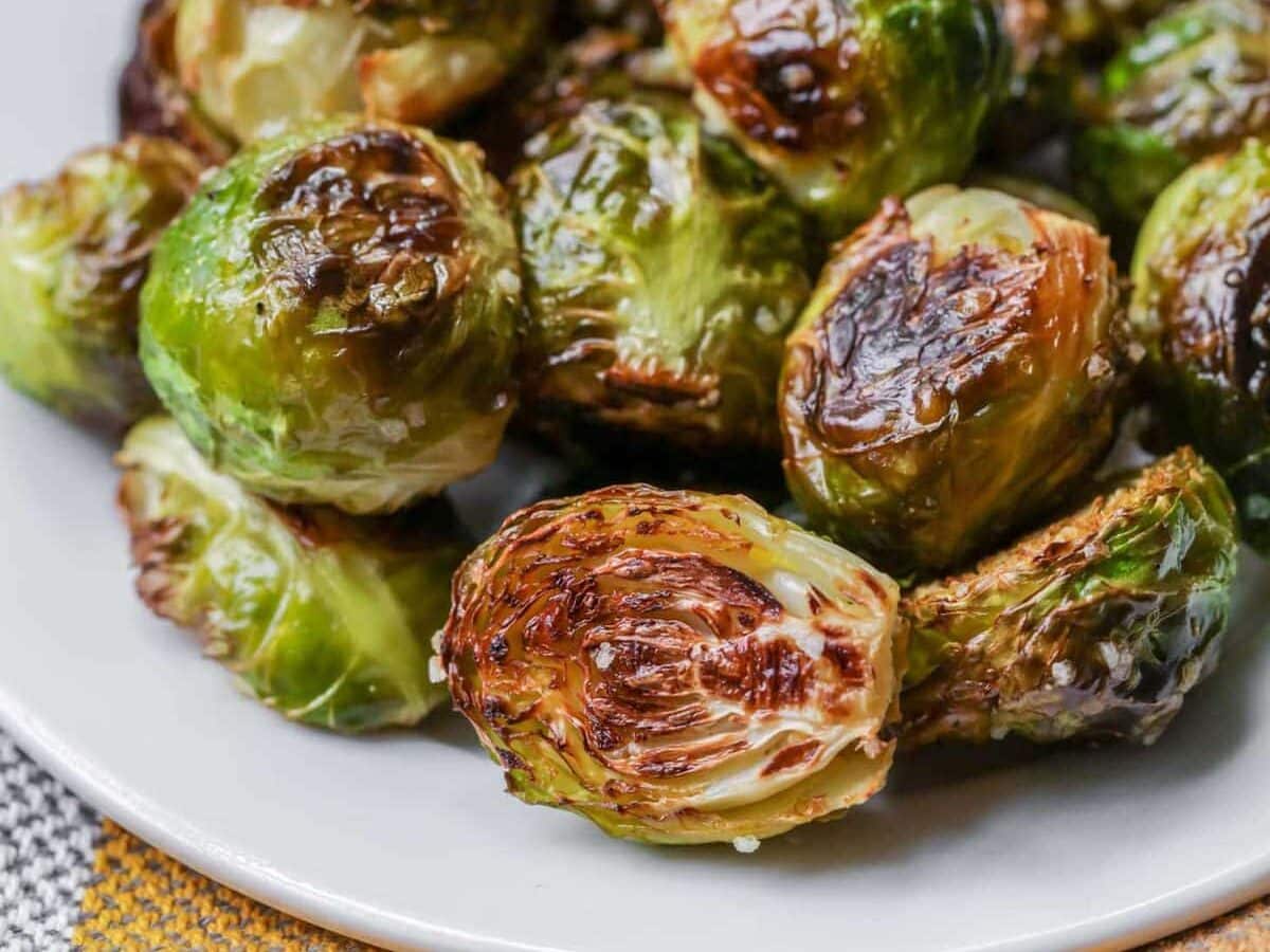 Roasted brussels sprouts with salt on top on white plate.