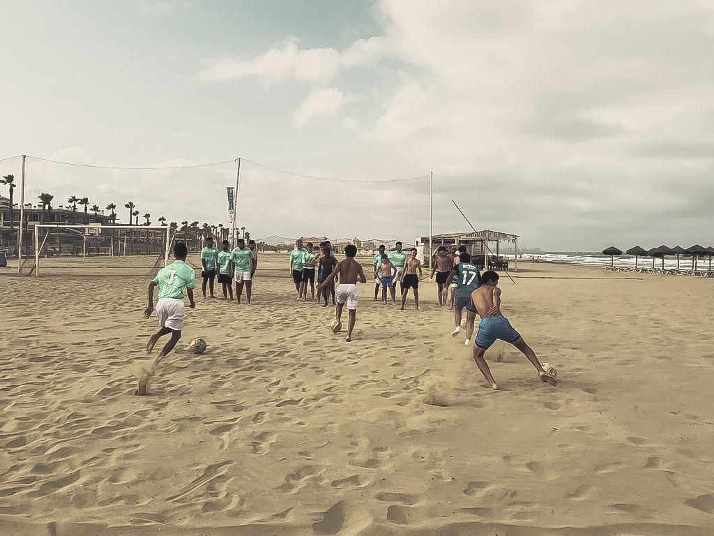 players on a beach training at a summer soccer camp