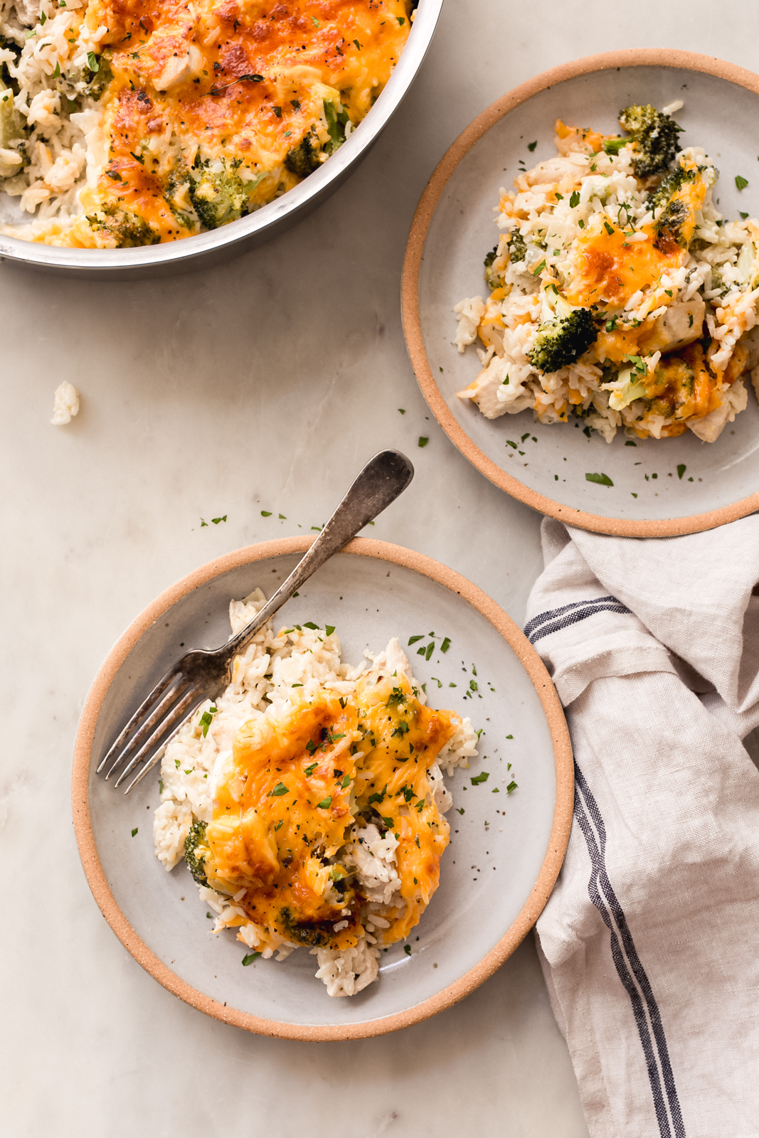 food scene with filled pan and plates of casserole on white marble