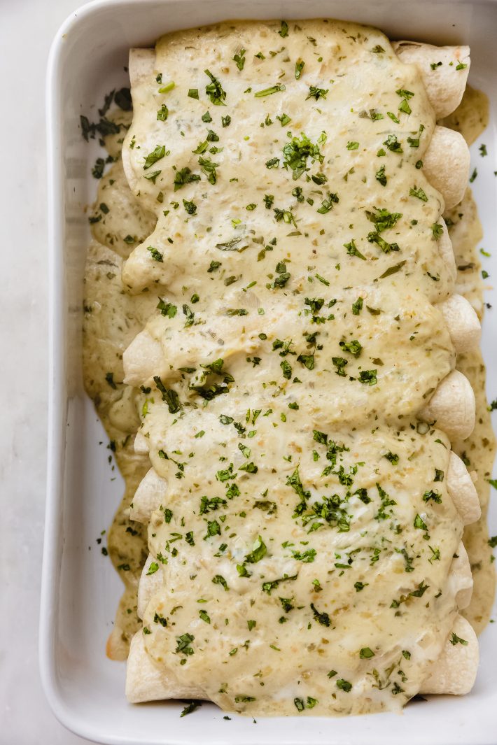 dish filled with enchiladas topped with tomatillo cream sauce