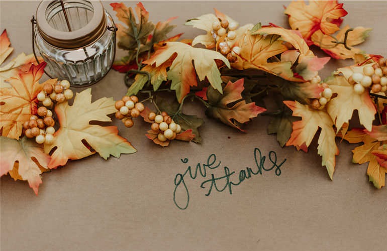 give thanks written on table with fall decor and candle