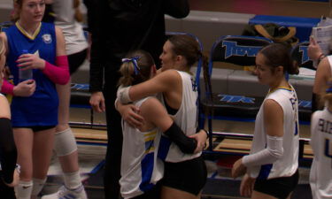 Two Ririe Bulldogs volleyball players hug on the sidelines.