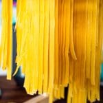 long pasta dough cut into noodles hang drying.