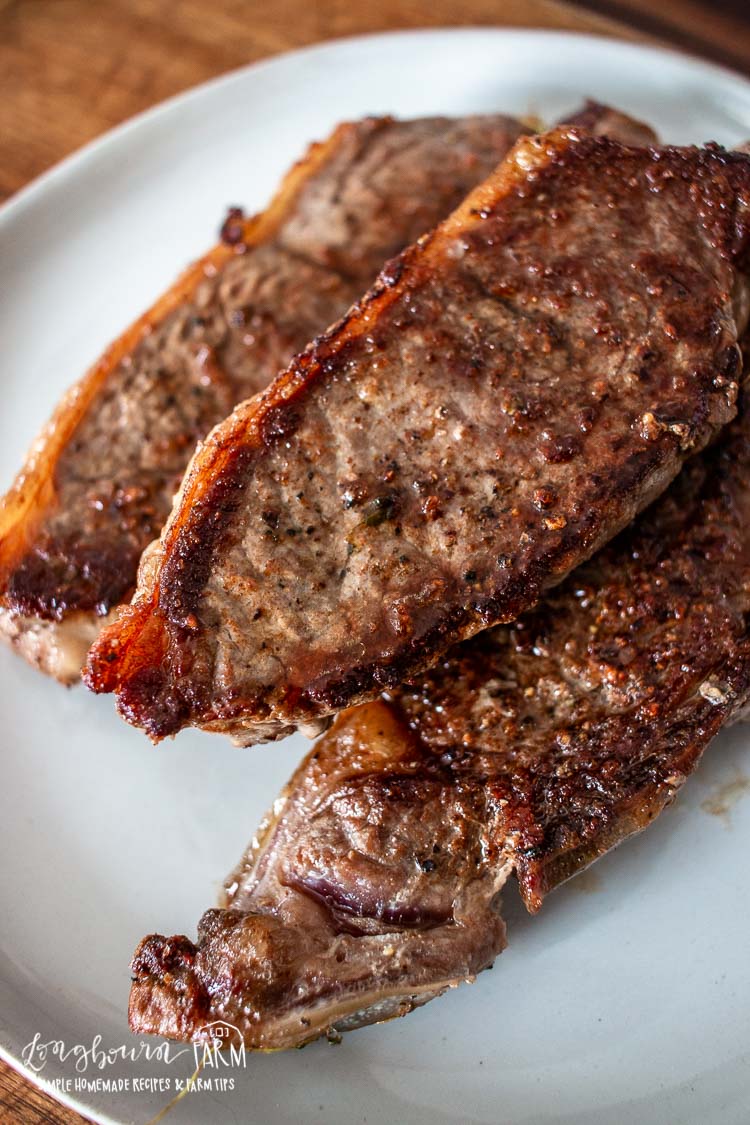 Close-up of three cooked steaks on a plate, their crispy, seasoned outer layer glistening. Slightly overlapping each other, these juicy cuts could perfectly complement a fresh steak salad with their delicious appearance.