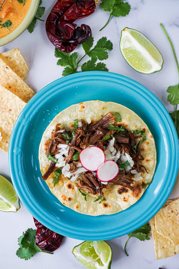 barbacoa, mexican shredded beef tacos with chips and queso, peppers, cilantro, and lime