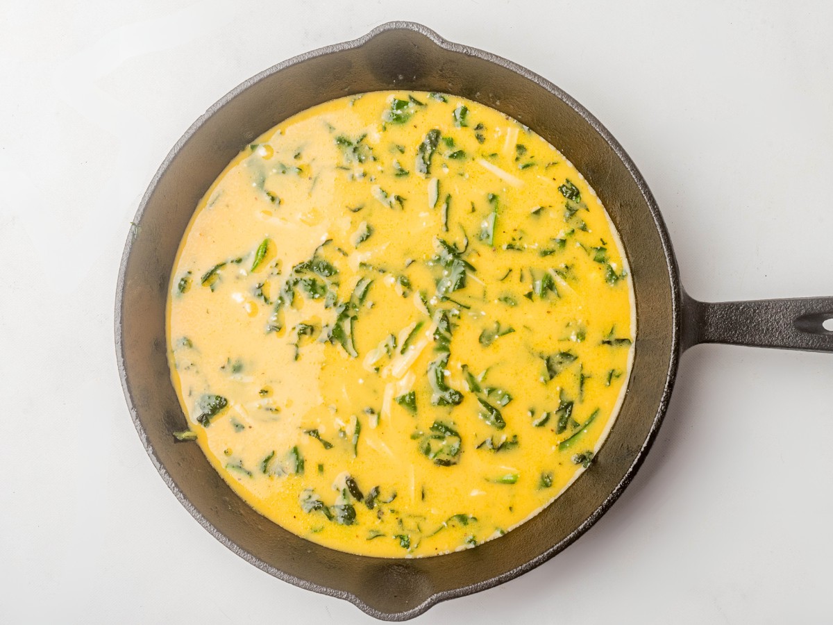 adding frittata batter to cast iron skillet.