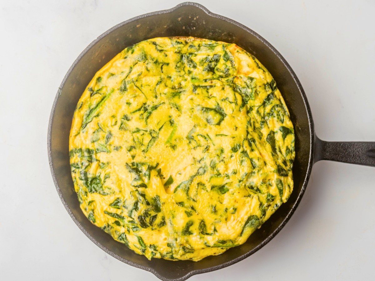 cooked spinach frittata in hot skillet pan.