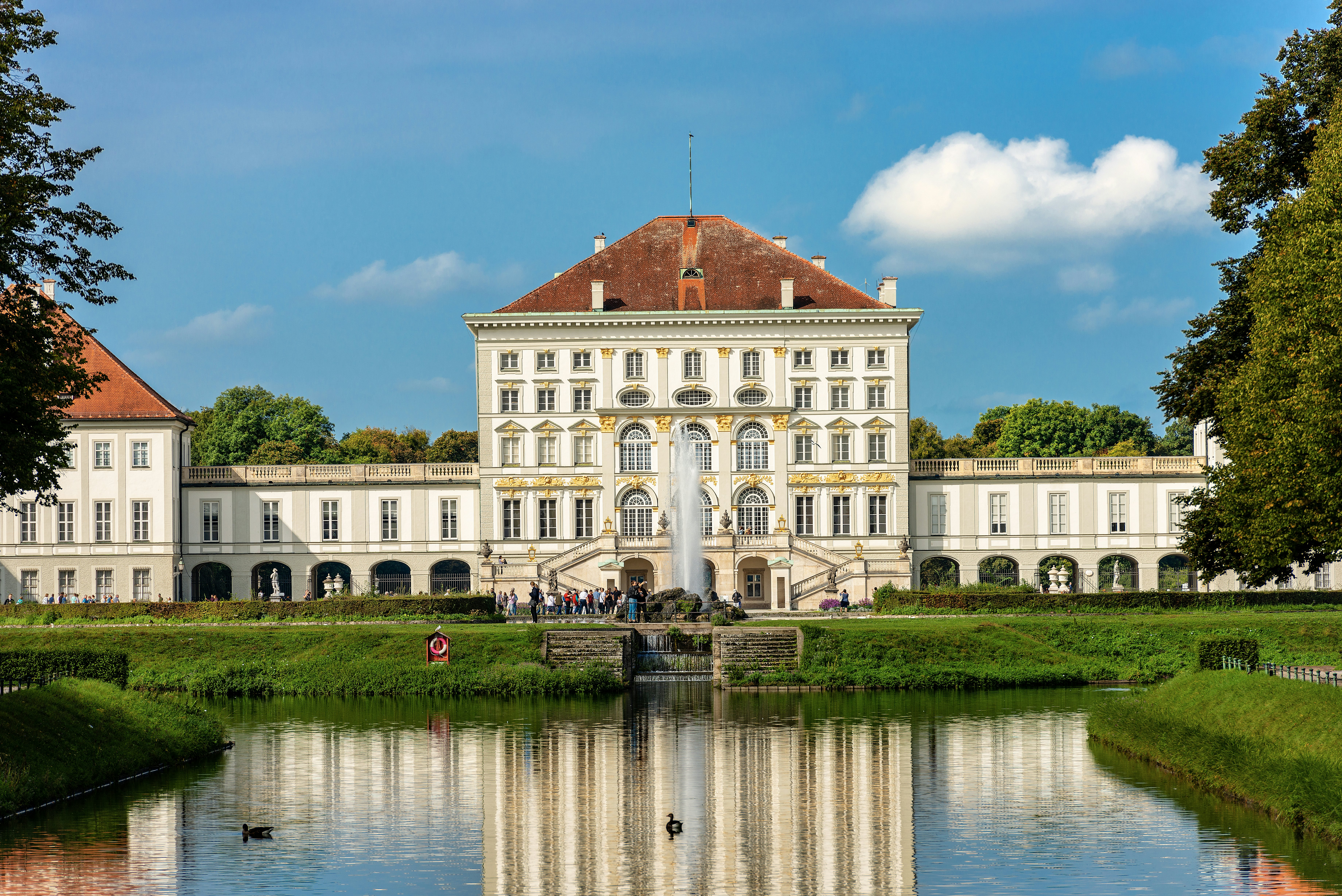 The exterior of a vast palace with people moving around on its terraces