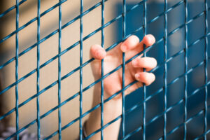 A child's hand holds on to a fence.