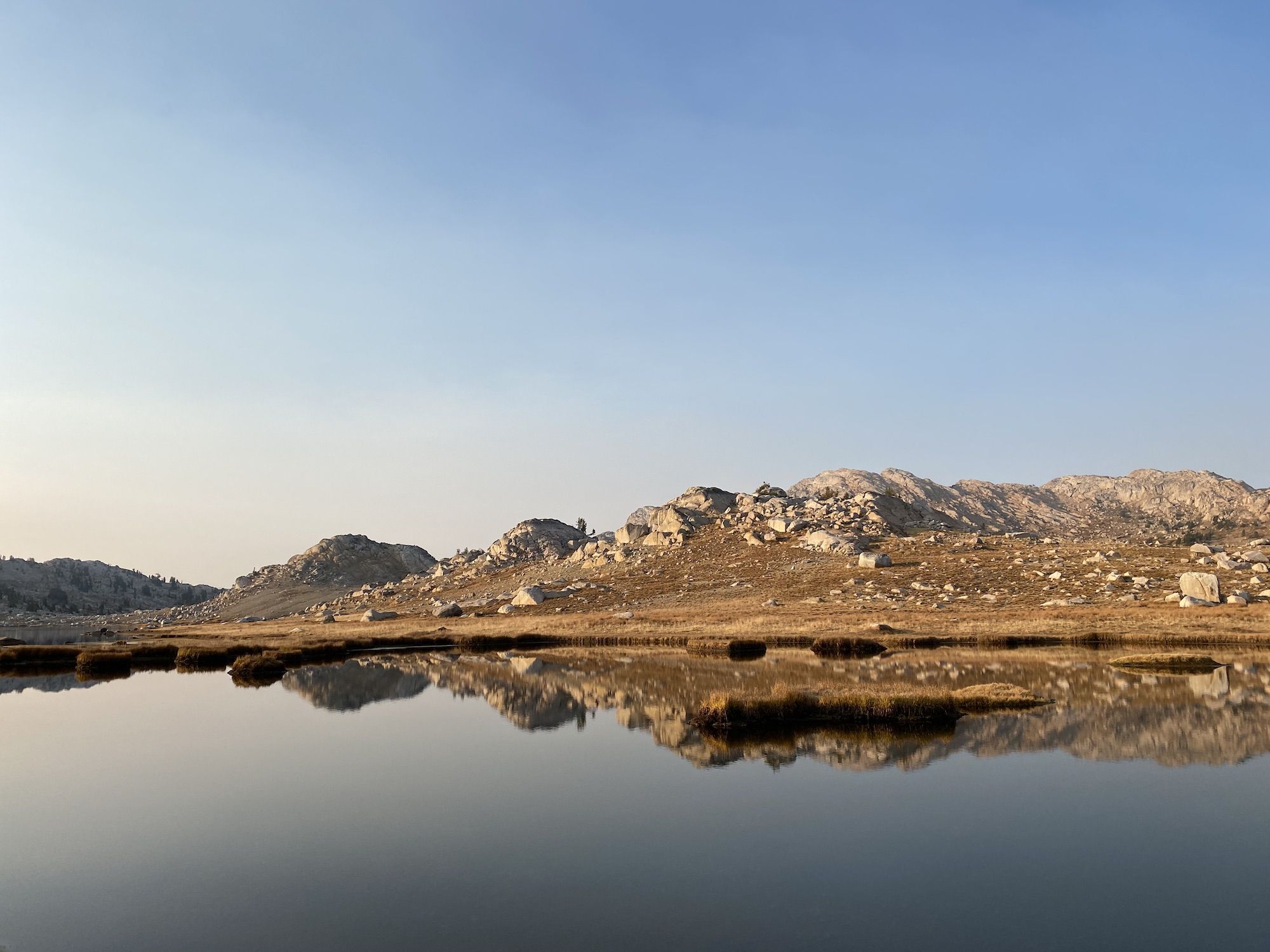 A calm lake reflecting the mountains behind it