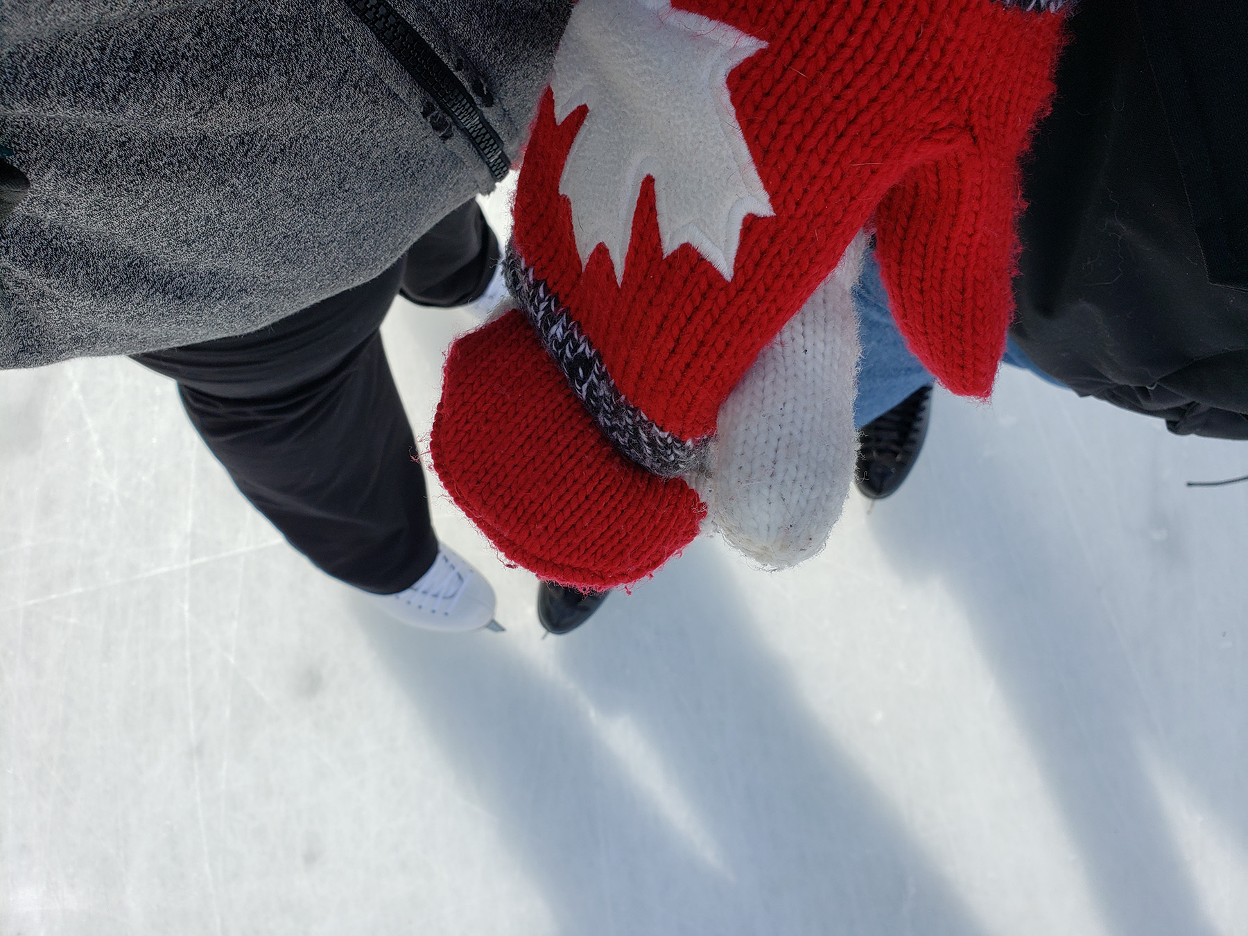 Glove hands held above skates and ice below.