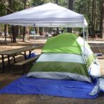 dining canopy partially over a picnic table and tent