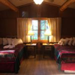 2 double beds, nightstands with lamps, window in a cabin bedroom