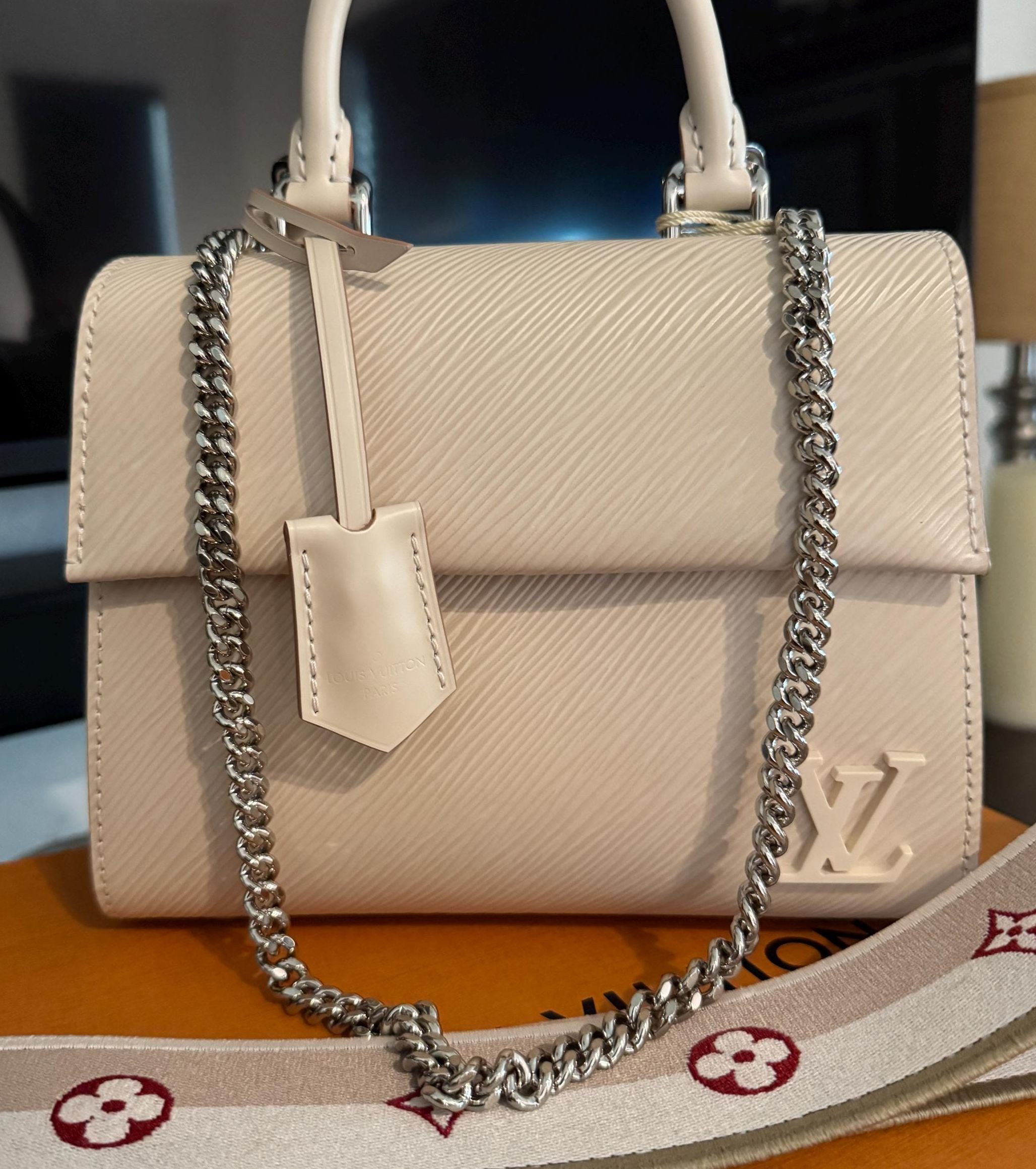 Beige LV handbag with luxurious chain strap.