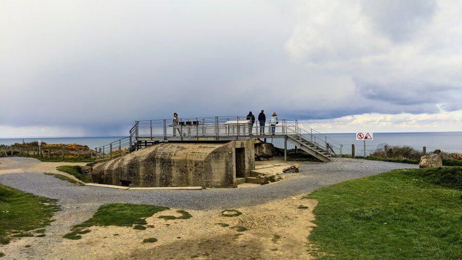 A concrete bunker with a modern steel viewing platform on top with visitors