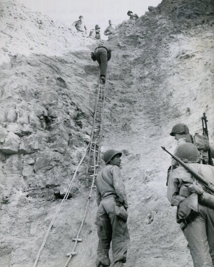 B&W photo of Rangers climbing up the cliff