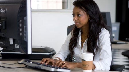 Student working on computer with cup of coffee