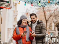 Couple on phones while talking walk outside during the winter