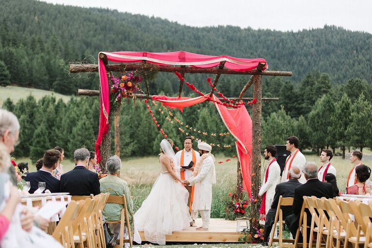 Couple exchanging vows beneath wood mandap in the mountains